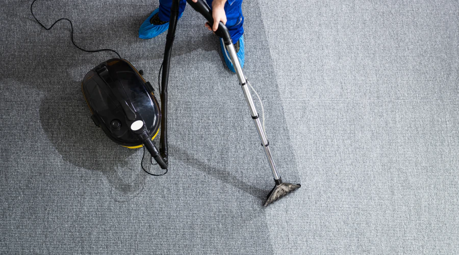 worker cleaning a grey carpet